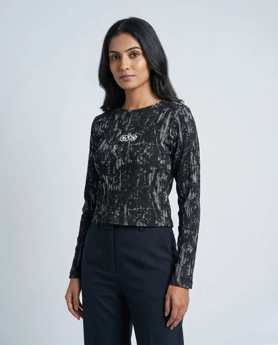 Woman wearing a black patterned long-sleeve top and black pants on a white background


