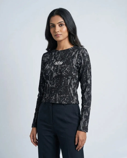 Woman wearing a black patterned long-sleeve top and black pants on a white background

