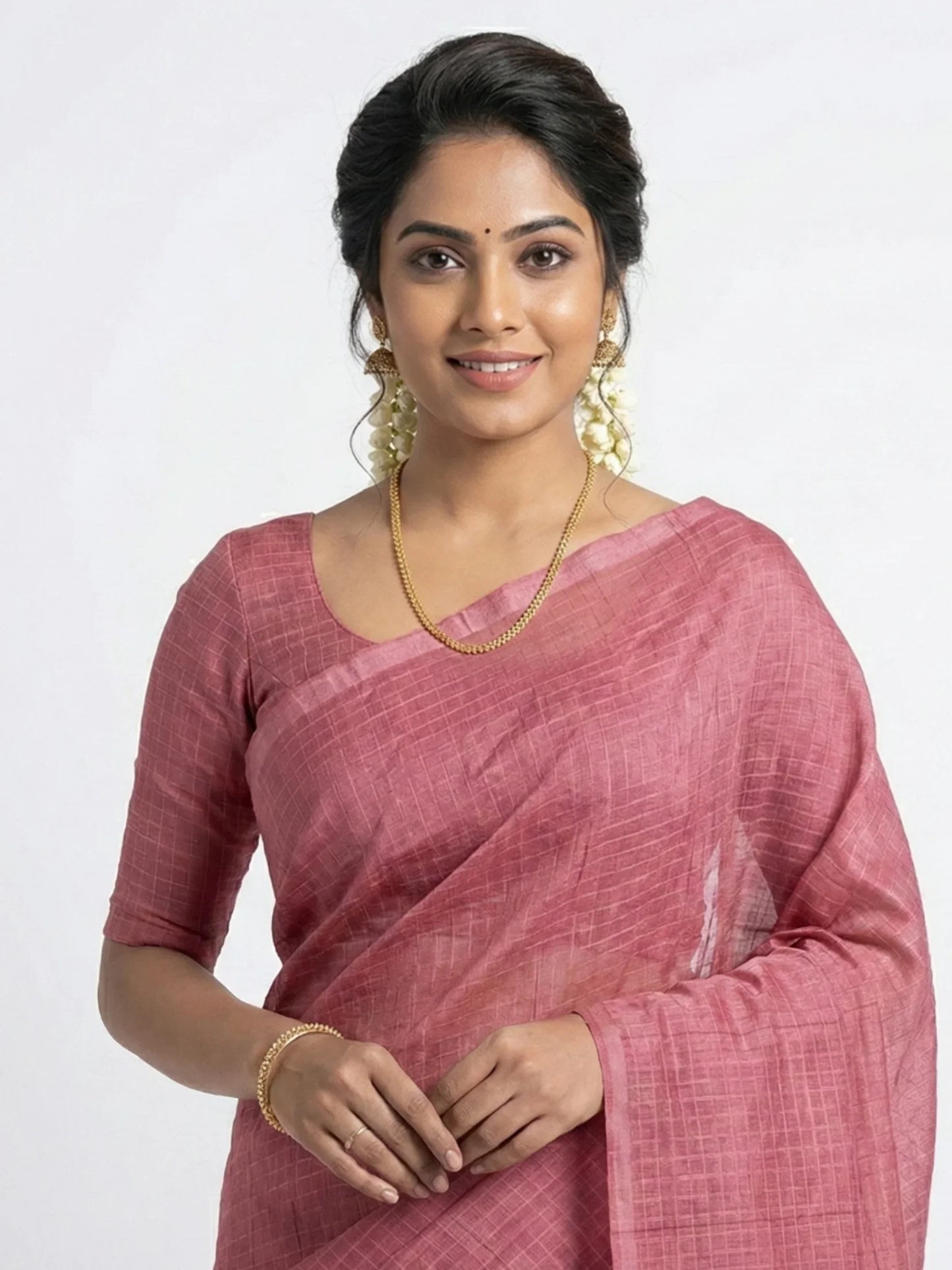 Woman wearing a pink saree with a plain background

