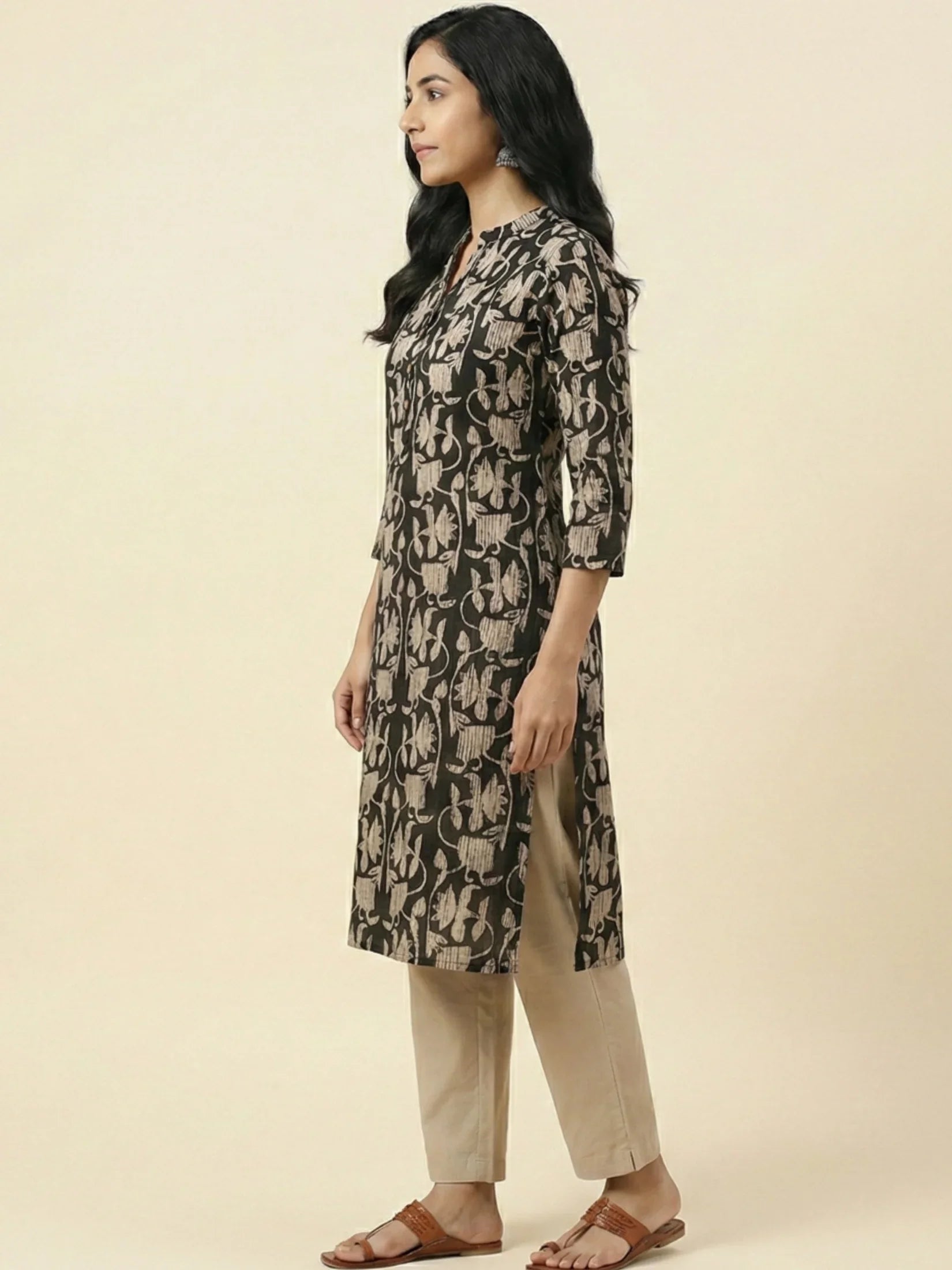 Woman wearing a black and beige patterned kurta with beige pants on a beige background

