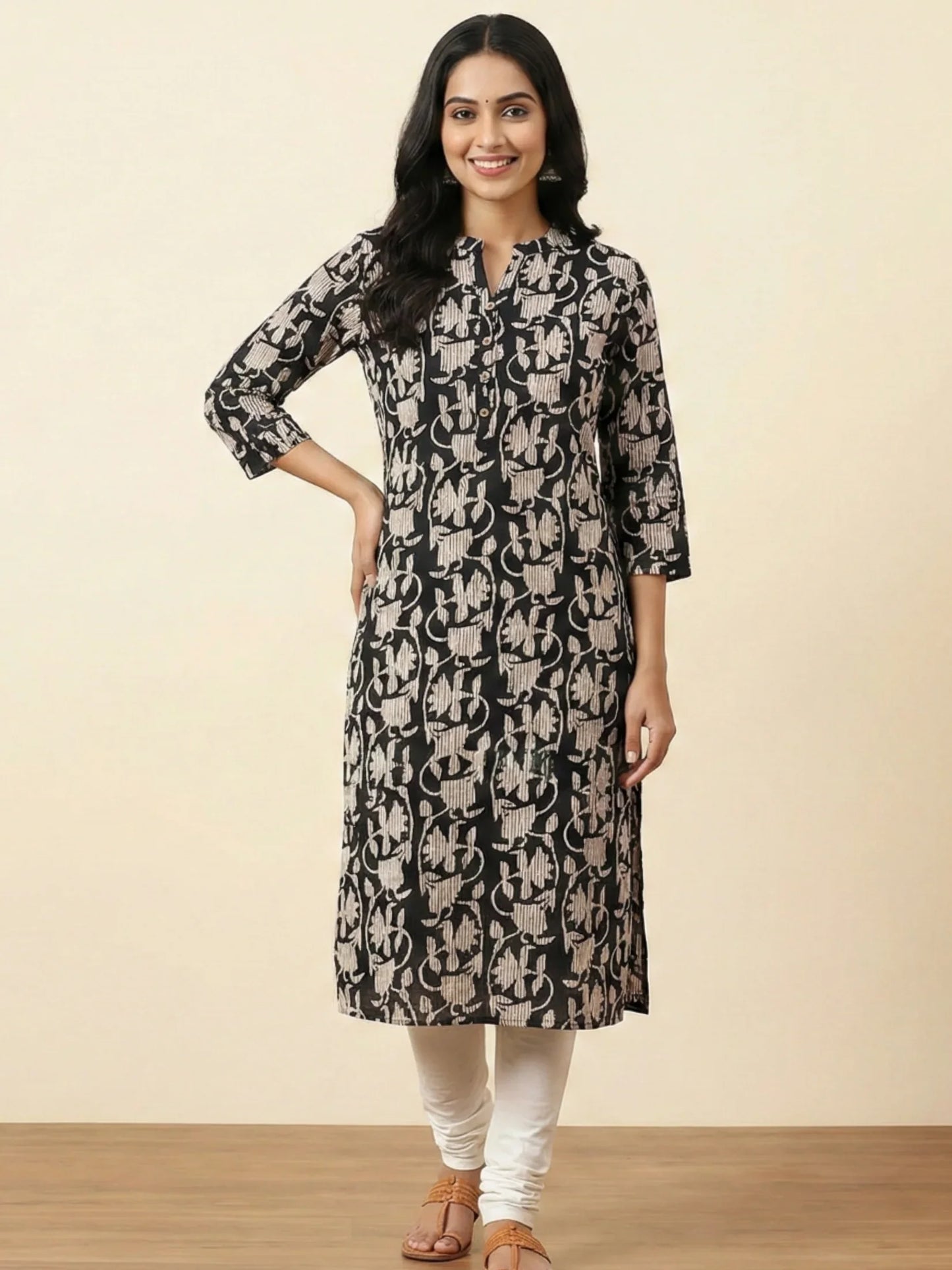 Woman wearing a black and beige patterned kurta with white pants on a beige background
