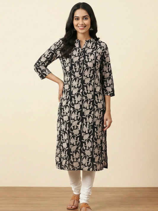 Woman wearing a black and beige patterned kurta with white pants on a beige background
