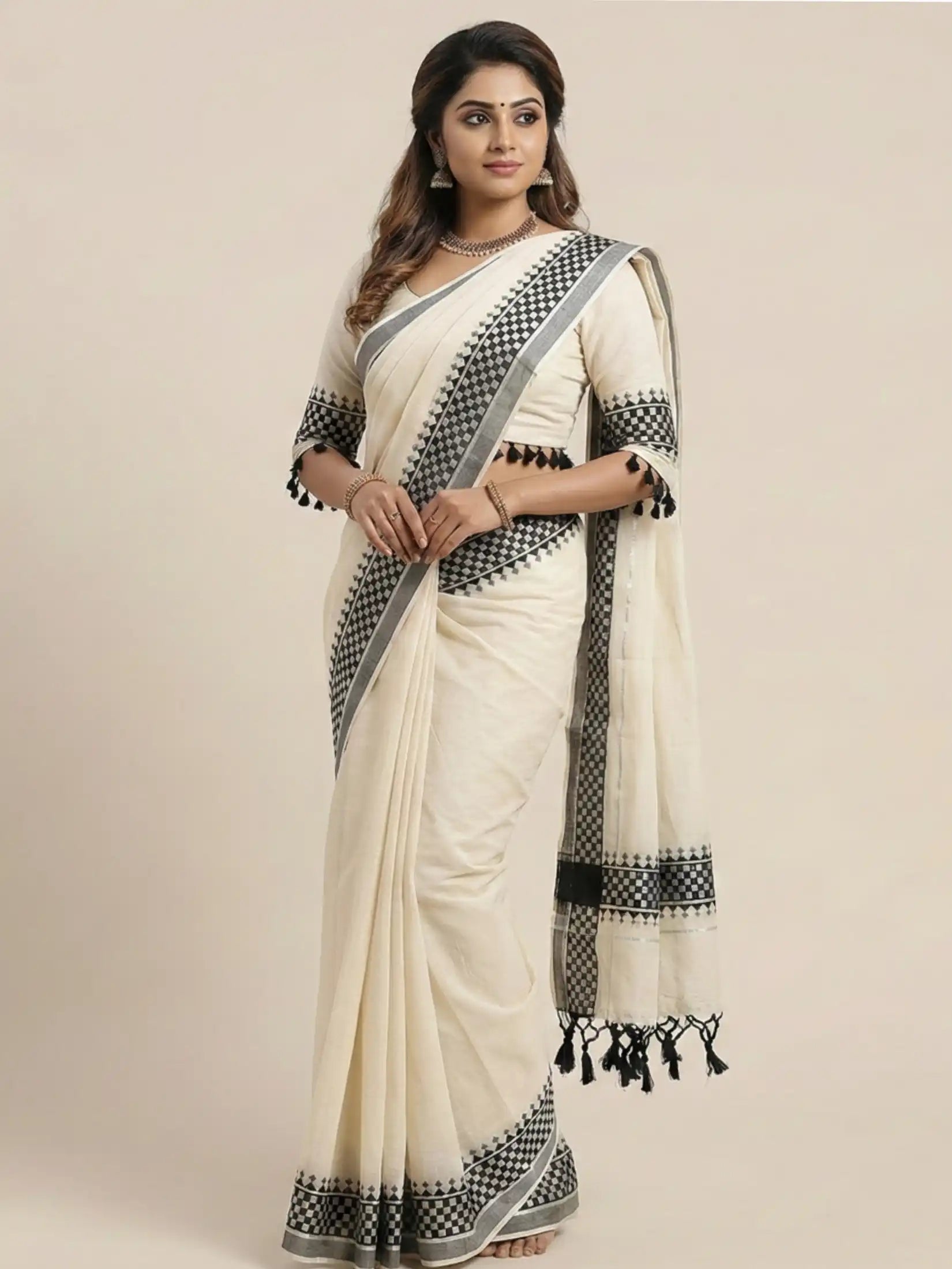 Woman wearing a white saree with black patterns on a beige background

