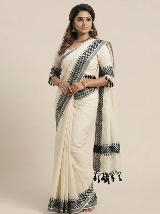 Woman wearing a white saree with black patterns on a beige background

