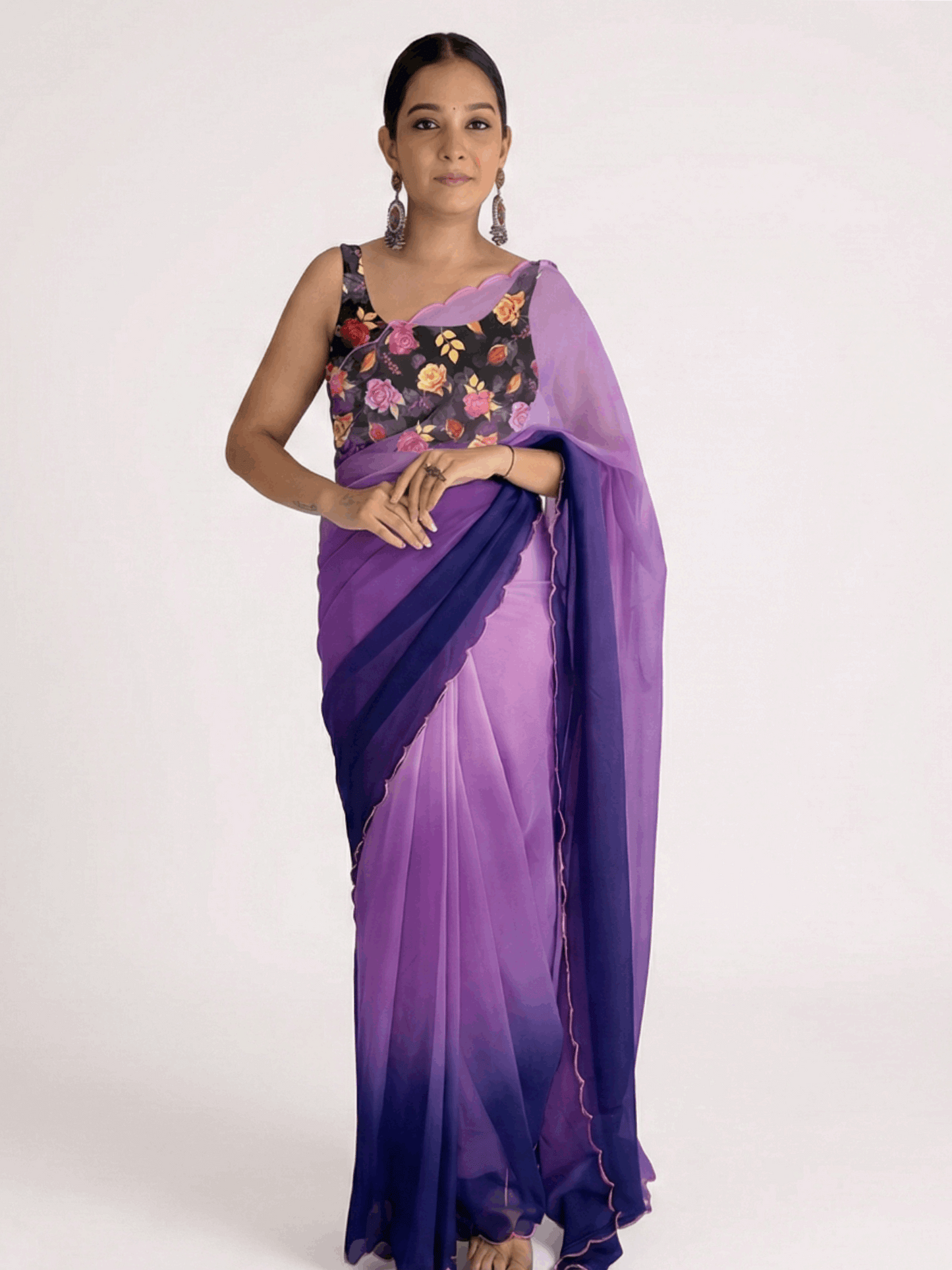 Woman wearing a purple saree with a floral blouse on a white background

