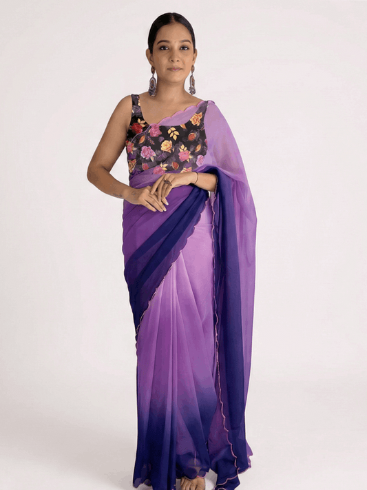 Woman wearing a purple saree with a floral blouse on a white background

