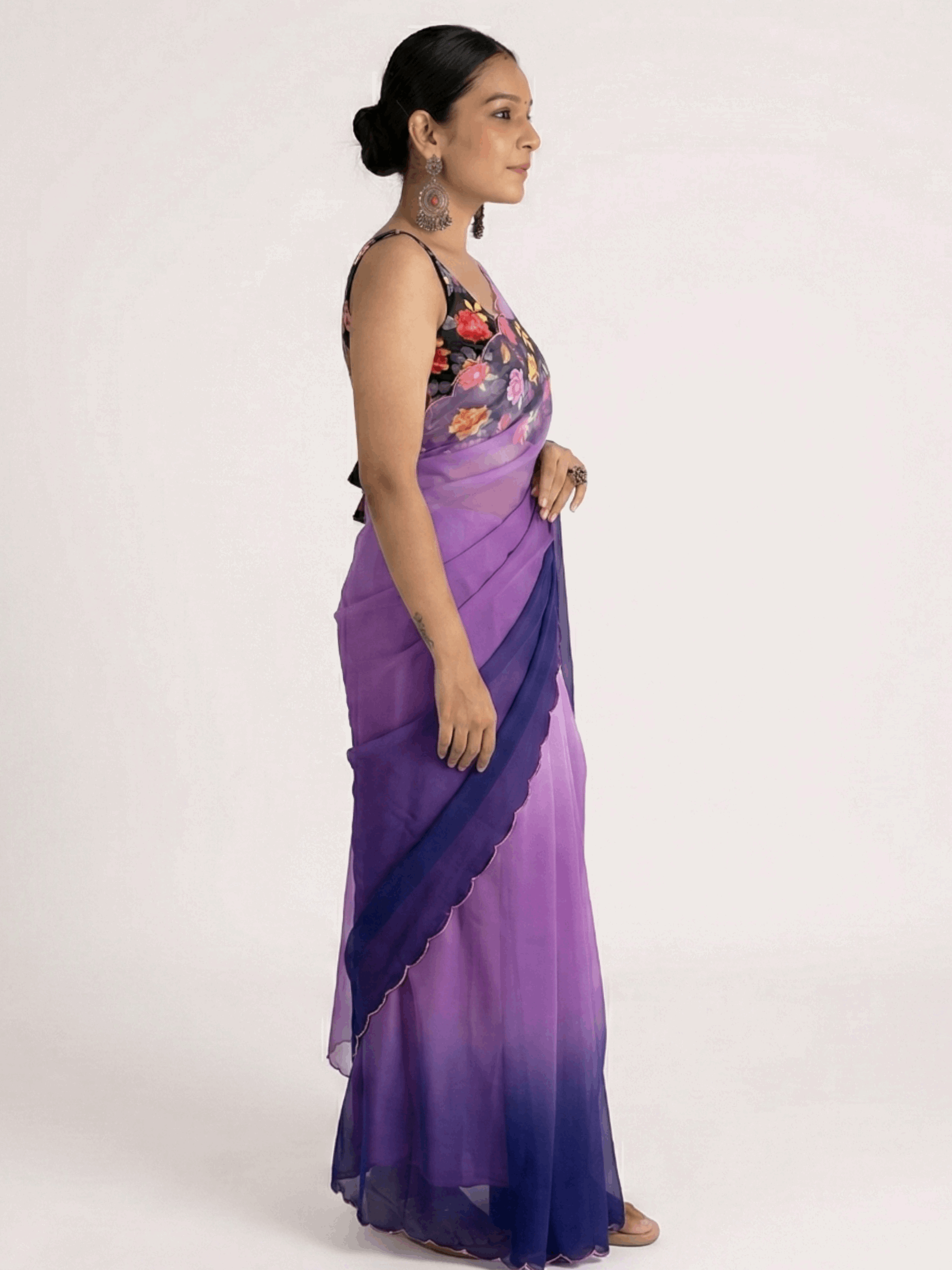 Woman wearing a purple ombre saree with a floral top on a white background

