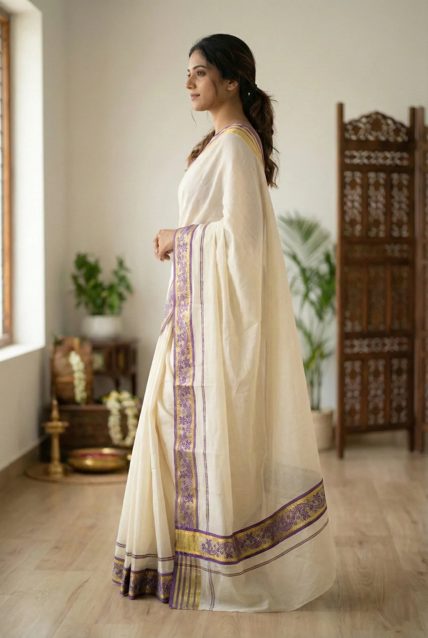 Side view of a premium Kerala set mundu showcasing the graceful drape and the intricate purple and gold floral embroidery on the border.