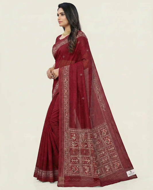 Side profile of a model showcasing the elegant drape and texture of a maroon traditional saree from Sherly's Attire.