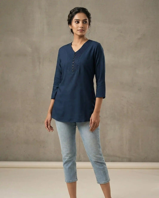 Woman wearing a navy blue top and light blue jeans against a plain background

