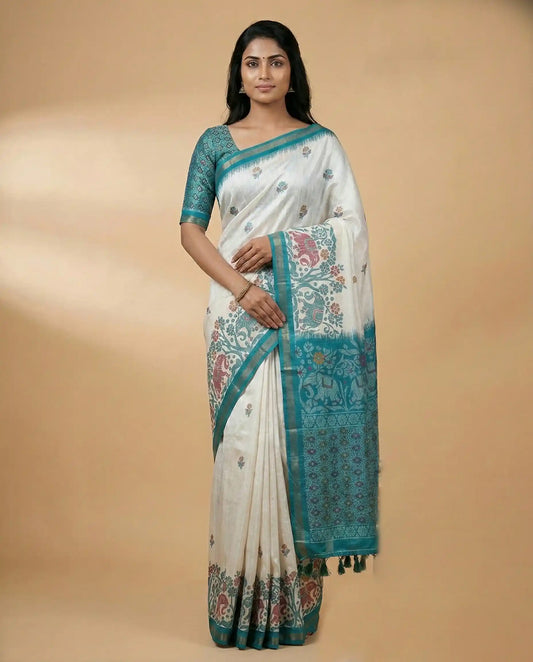 Woman wearing a white saree with blue patterns on a beige background
