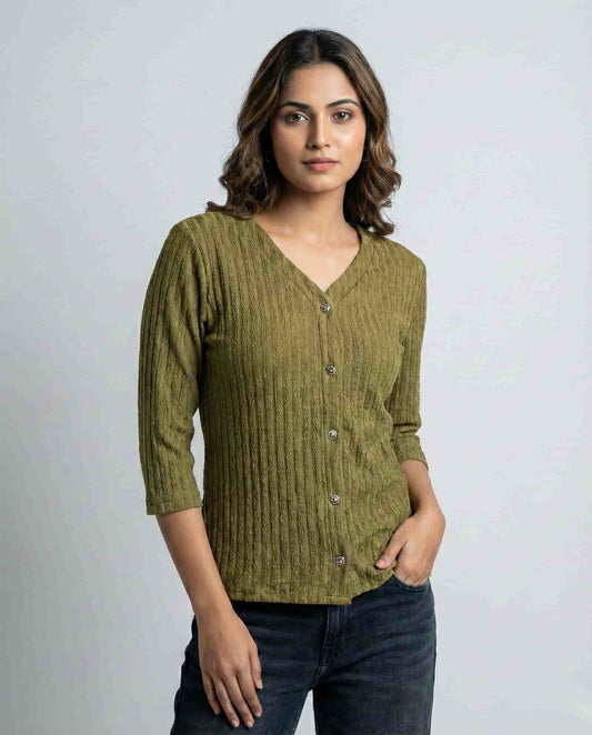 Woman wearing a green ribbed sweater against a plain background

