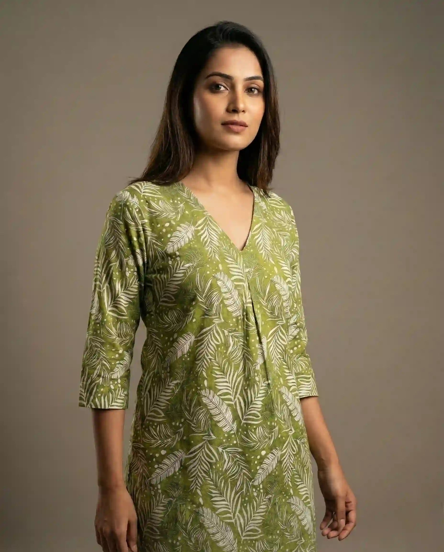 Woman wearing a green patterned dress against a plain background

