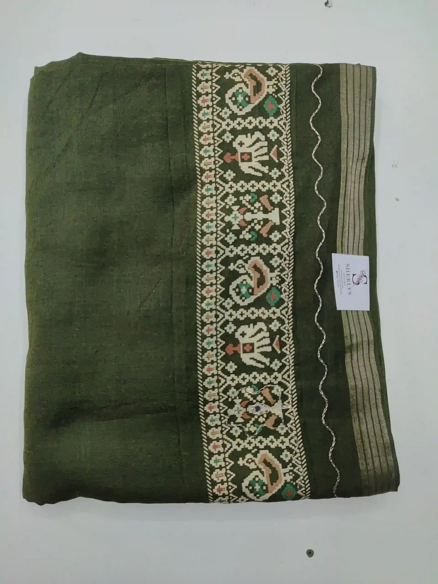 Green saree with intricate white embroidery on a white background
