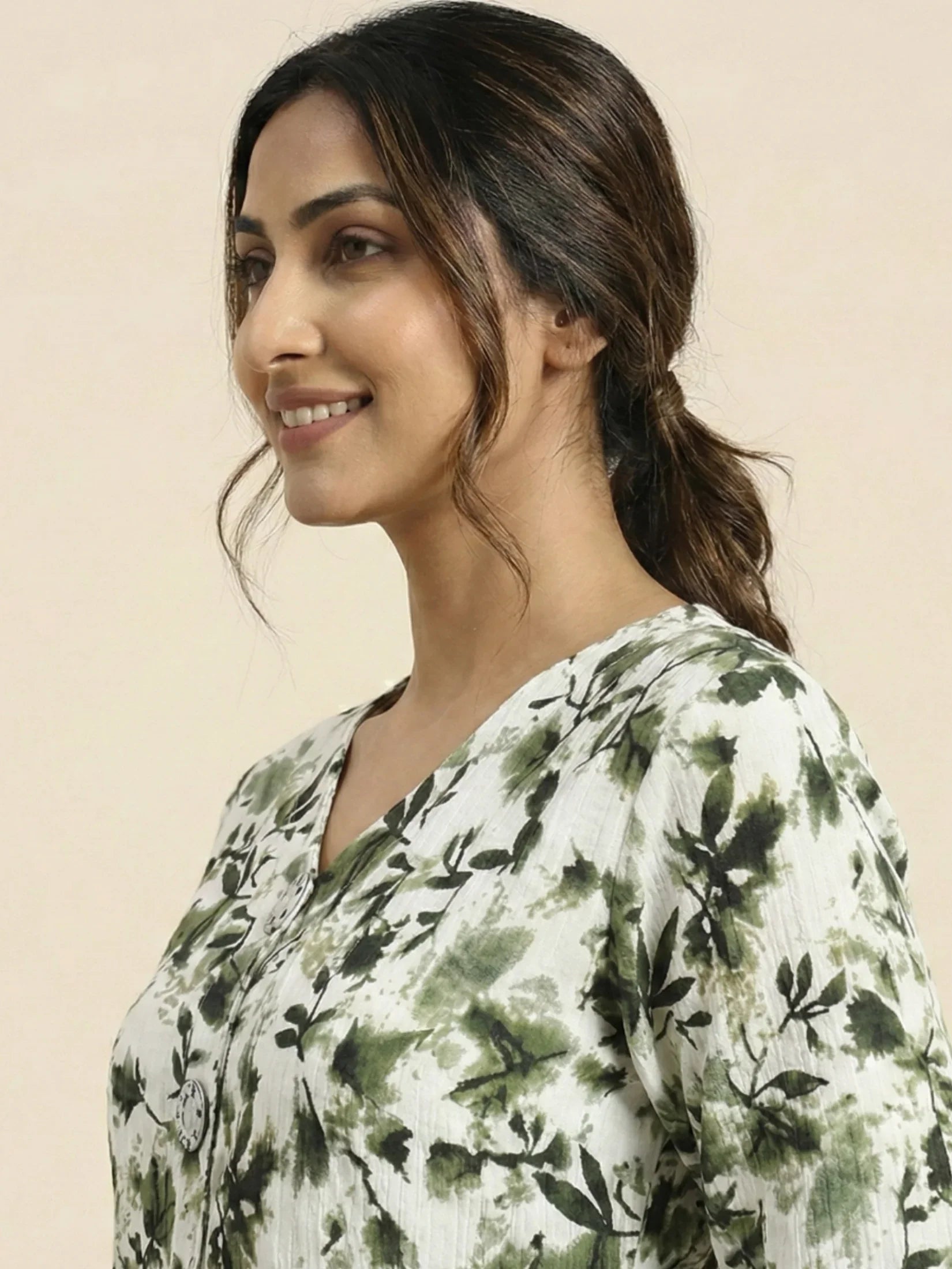 Woman wearing a green and white floral dress against a beige background

