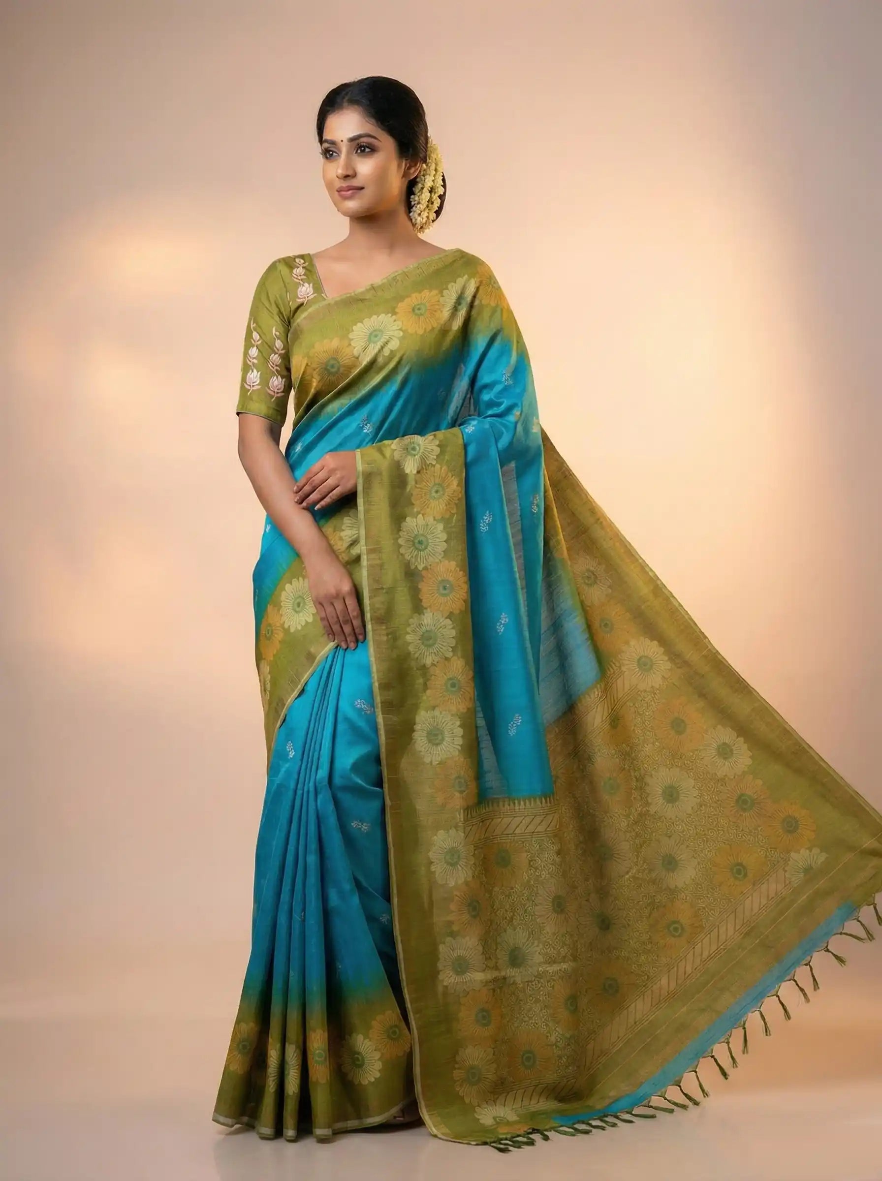 Woman wearing a blue and green saree with a plain background

