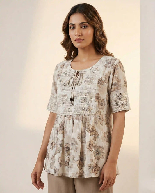 Woman wearing a floral blouse against a plain background

