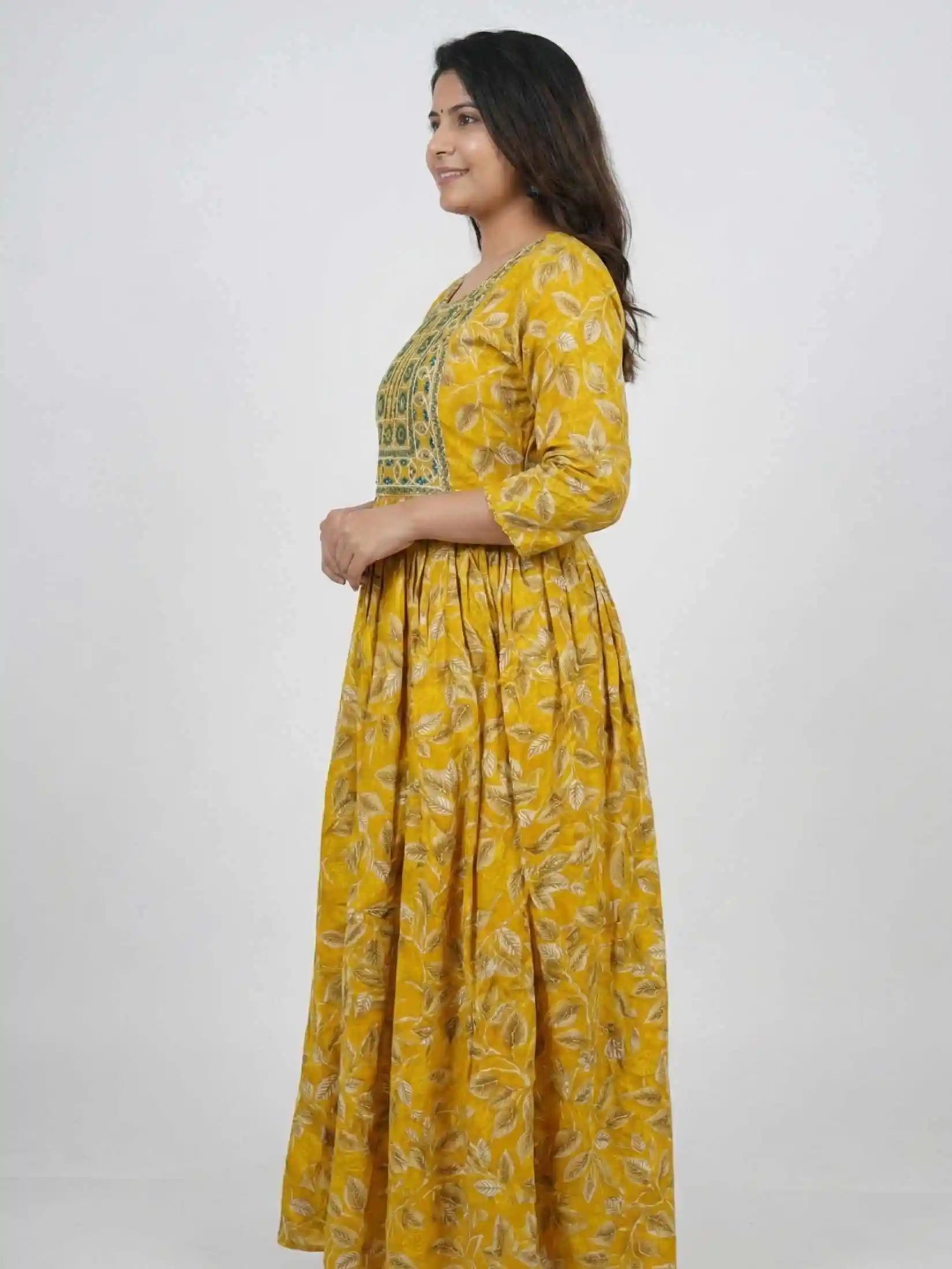 Woman wearing a yellow floral dress against a white background

